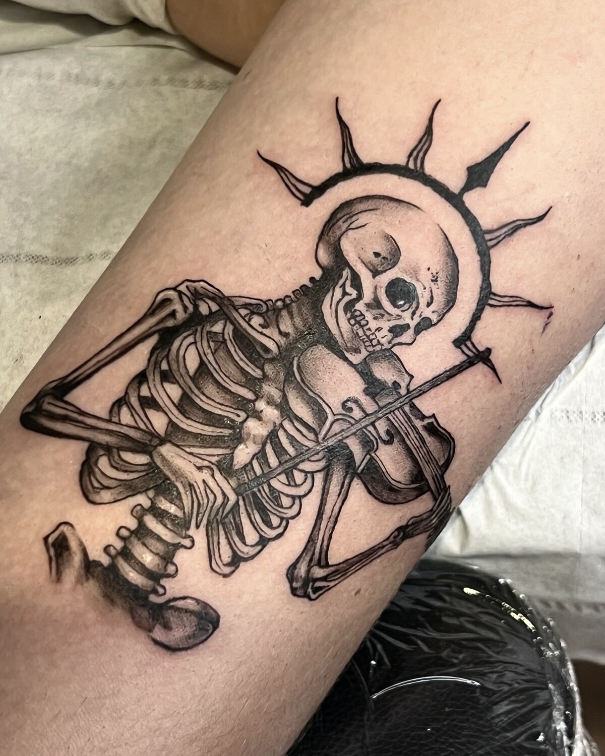 Squelette et soleil rayonnant, tatouage blackwork sur le bras