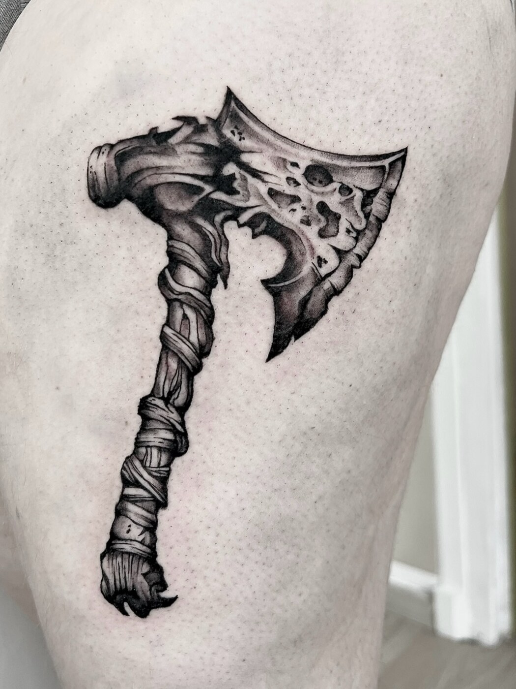 Hache de guerre ornée, tatouage noir et gris sur la cuisse